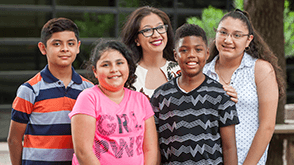 A principal who completed a program with CES stands with with her students 